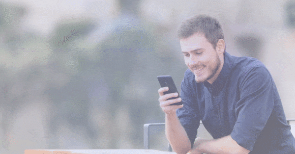 Animated GIF showing a man sitting at an outdoor table, smiling as he looks at his smartphone. The image suggests a relaxed, positive experience, potentially representing the ease and convenience of using a mobile app and getting an app with OmniShop. The text that goes is: You want a mobile app for your store? Get it easy and fast.